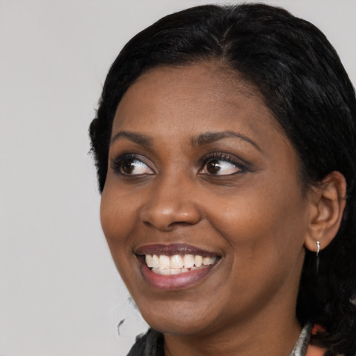 Joyful black young-adult female with long  black hair and brown eyes