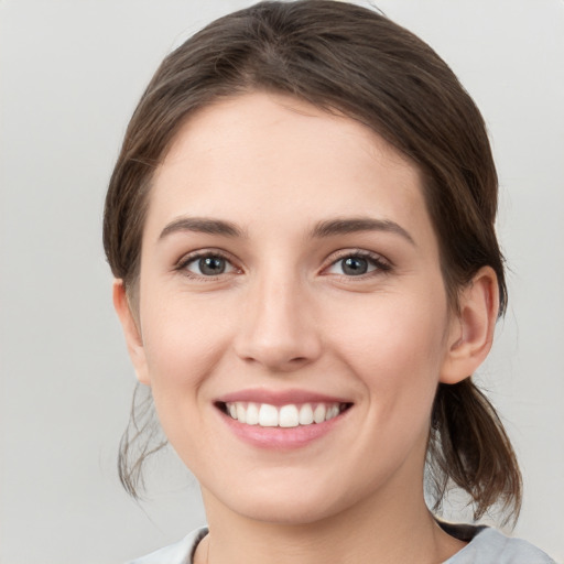 Joyful white young-adult female with medium  brown hair and grey eyes