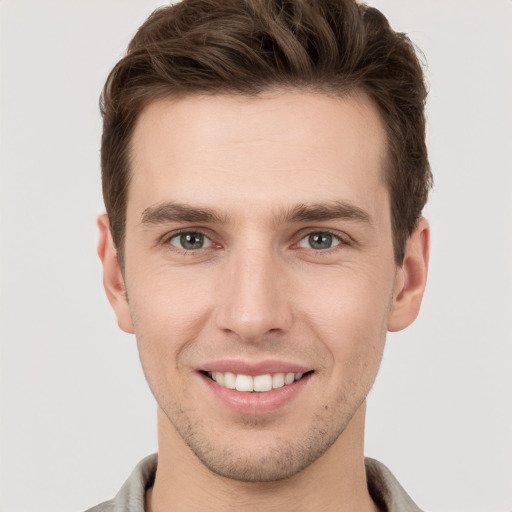 Joyful white young-adult male with short  brown hair and grey eyes