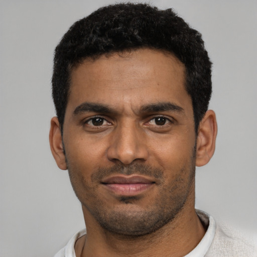 Joyful black young-adult male with short  black hair and brown eyes