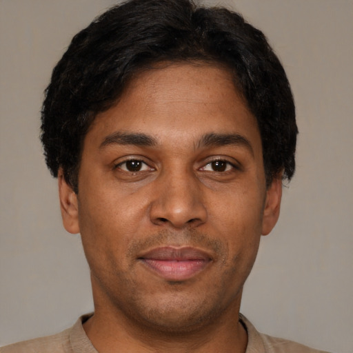 Joyful latino young-adult male with short  brown hair and brown eyes