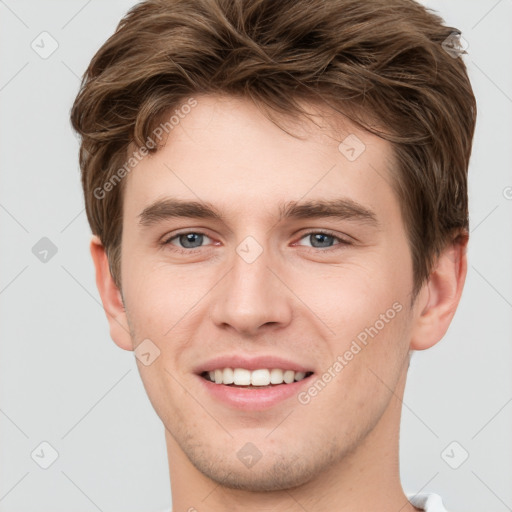 Joyful white young-adult male with short  brown hair and grey eyes