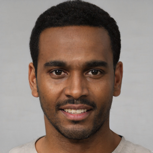 Joyful black young-adult male with short  black hair and brown eyes