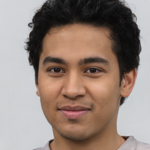 Joyful latino young-adult male with short  brown hair and brown eyes