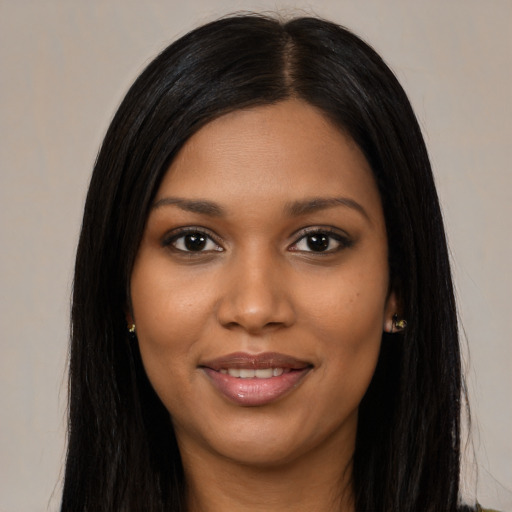 Joyful black young-adult female with long  black hair and brown eyes