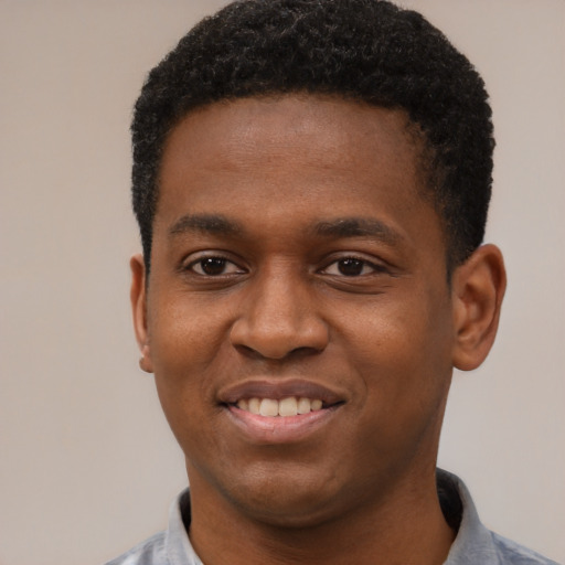 Joyful black young-adult male with short  black hair and brown eyes