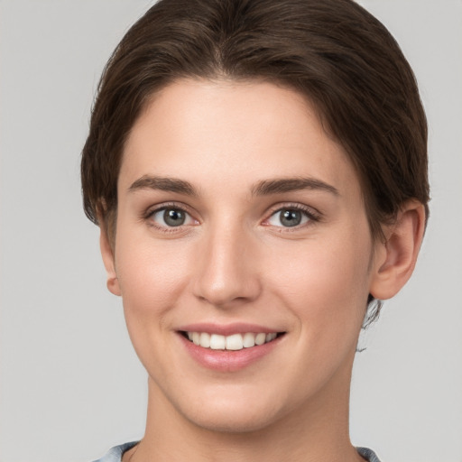 Joyful white young-adult female with short  brown hair and grey eyes