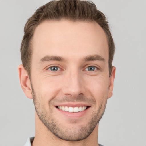 Joyful white young-adult male with short  brown hair and grey eyes