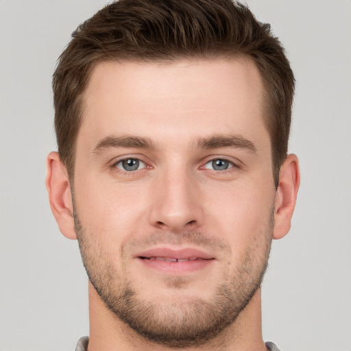 Joyful white young-adult male with short  brown hair and grey eyes