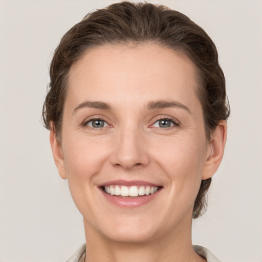 Joyful white young-adult female with medium  brown hair and grey eyes