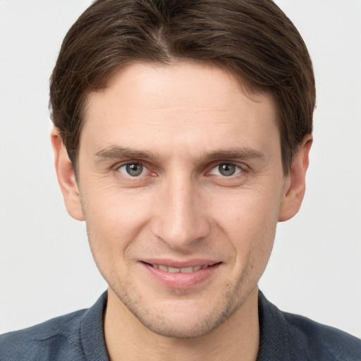 Joyful white young-adult male with short  brown hair and grey eyes