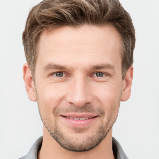 Joyful white young-adult male with short  brown hair and grey eyes