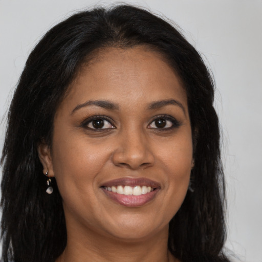 Joyful black young-adult female with long  brown hair and brown eyes