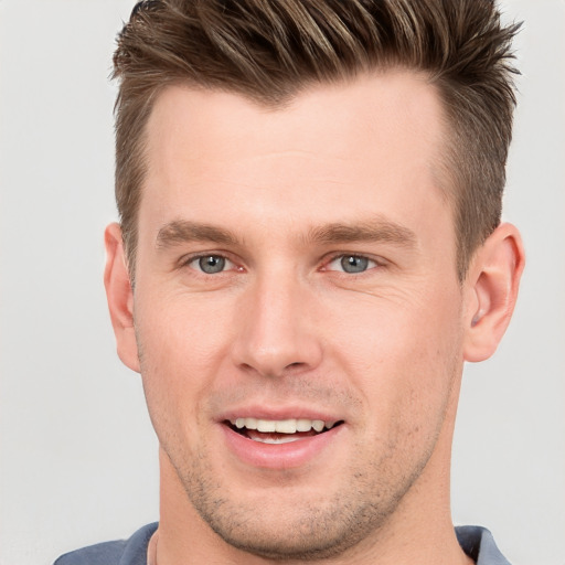 Joyful white young-adult male with short  brown hair and grey eyes