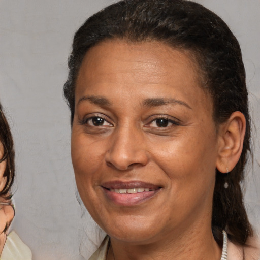 Joyful black adult female with medium  brown hair and brown eyes