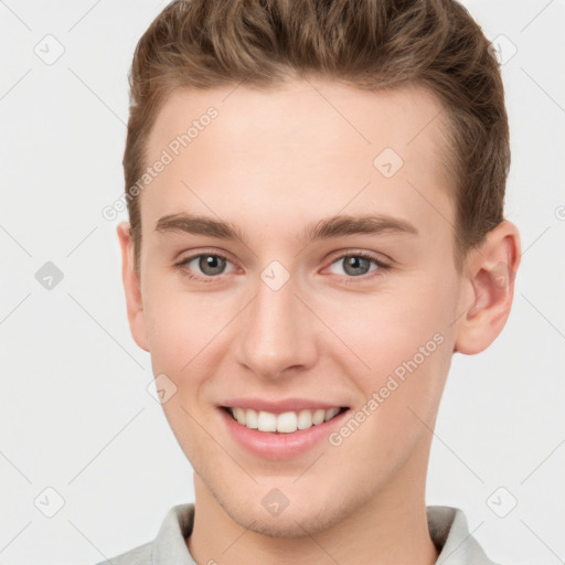 Joyful white young-adult male with short  brown hair and grey eyes