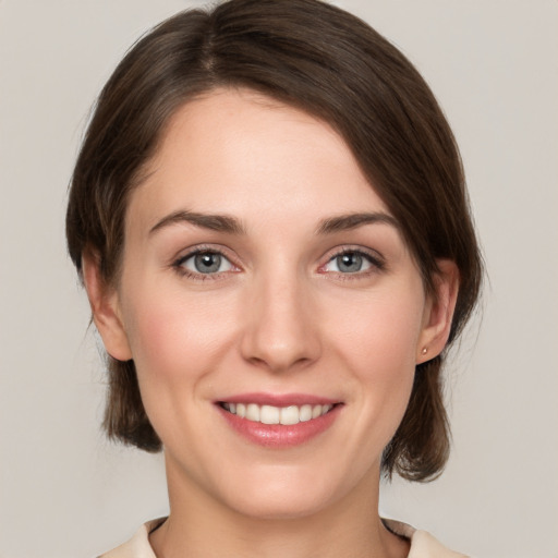 Joyful white young-adult female with medium  brown hair and grey eyes