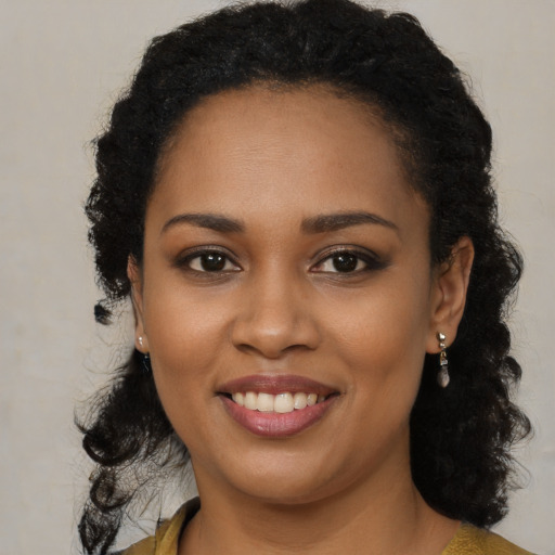 Joyful black young-adult female with long  brown hair and brown eyes