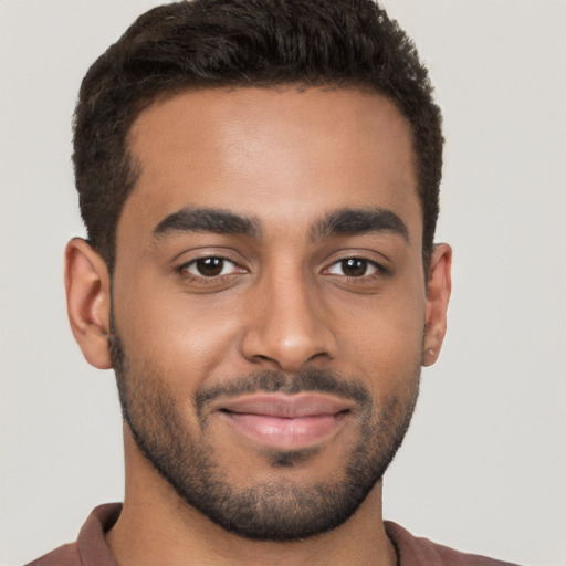 Joyful black young-adult male with short  brown hair and brown eyes