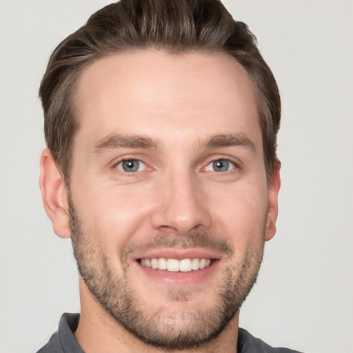 Joyful white young-adult male with short  brown hair and grey eyes