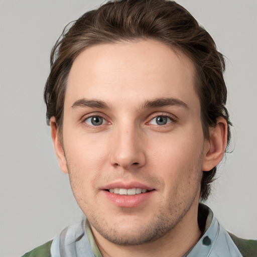 Joyful white young-adult male with medium  brown hair and grey eyes