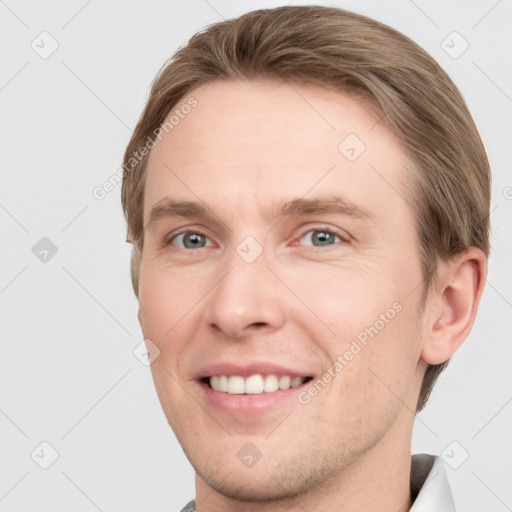 Joyful white young-adult male with short  brown hair and grey eyes