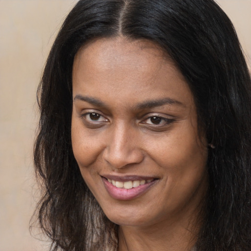 Joyful black young-adult female with long  brown hair and brown eyes