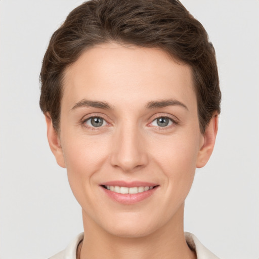 Joyful white young-adult female with short  brown hair and grey eyes