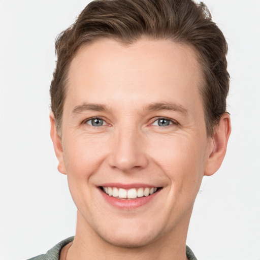 Joyful white young-adult male with short  brown hair and grey eyes