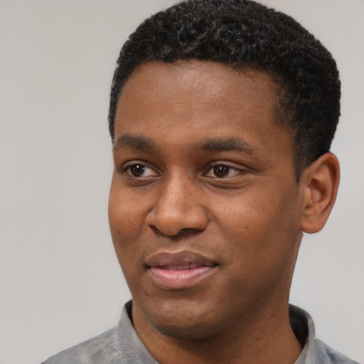 Joyful black young-adult male with short  black hair and brown eyes