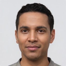 Joyful latino young-adult male with short  black hair and brown eyes