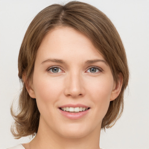 Joyful white young-adult female with medium  brown hair and grey eyes