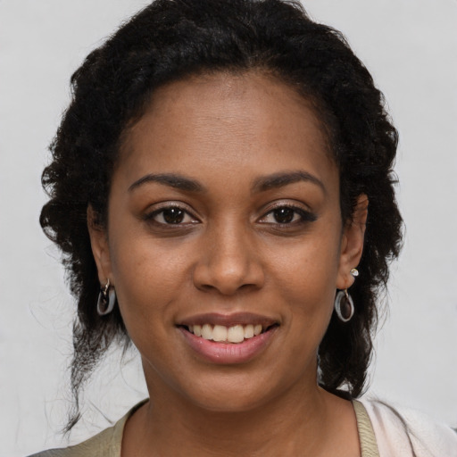 Joyful black young-adult female with long  black hair and brown eyes