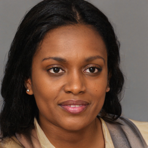 Joyful black young-adult female with long  brown hair and brown eyes
