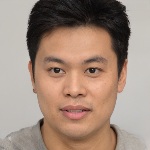 Joyful asian young-adult male with short  brown hair and brown eyes