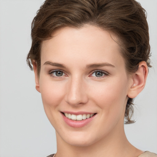 Joyful white young-adult female with short  brown hair and grey eyes