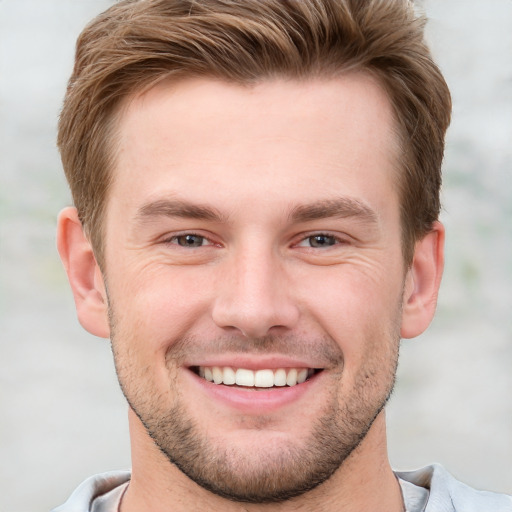 Joyful white young-adult male with short  brown hair and grey eyes