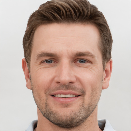 Joyful white young-adult male with short  brown hair and grey eyes