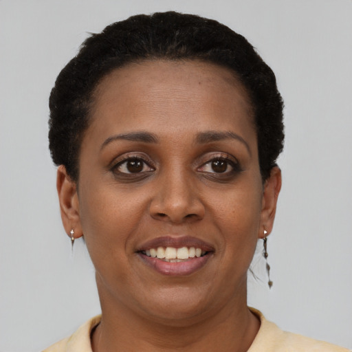 Joyful black young-adult female with short  black hair and brown eyes