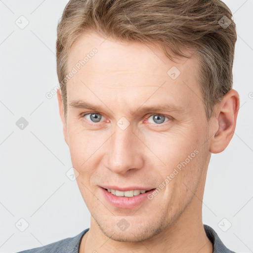 Joyful white young-adult male with short  brown hair and grey eyes