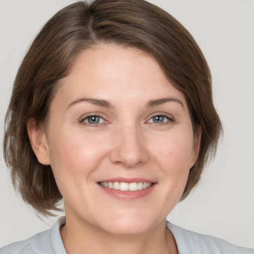 Joyful white young-adult female with medium  brown hair and grey eyes