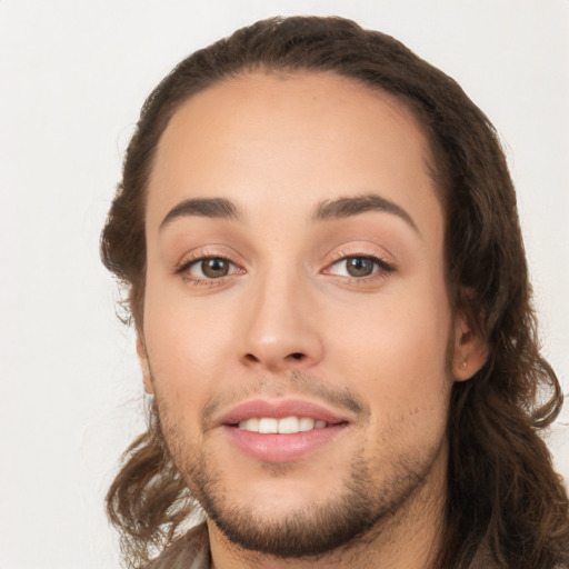 Joyful white young-adult male with long  brown hair and brown eyes