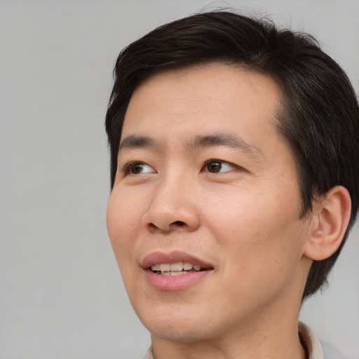 Joyful asian adult male with short  brown hair and brown eyes