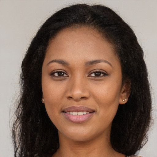 Joyful black young-adult female with long  brown hair and brown eyes