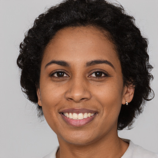 Joyful black young-adult female with long  black hair and brown eyes