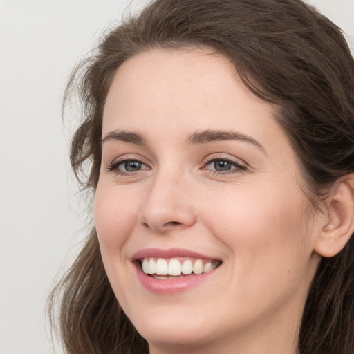 Joyful white young-adult female with long  brown hair and grey eyes