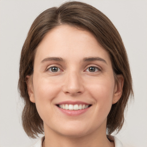 Joyful white young-adult female with medium  brown hair and grey eyes