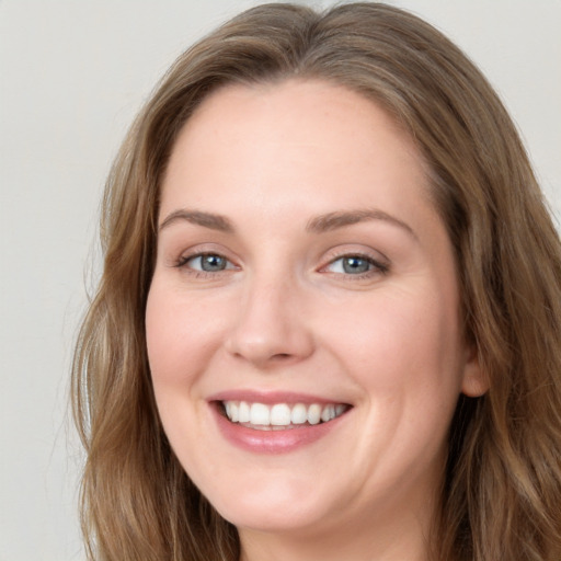 Joyful white young-adult female with long  brown hair and blue eyes