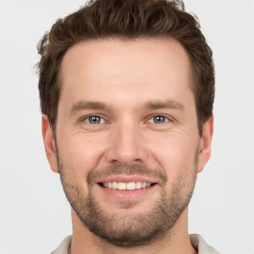 Joyful white young-adult male with short  brown hair and grey eyes