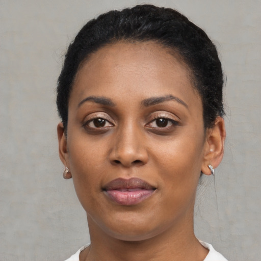 Joyful black young-adult female with short  black hair and brown eyes